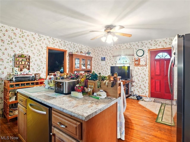 3912 Austinburg Rd, Ashtabula, OH 44004 - kitchen with appliances with stainless steel finishes, wallpapered walls, light wood finished floors, a kitchen island, and a ceiling fan