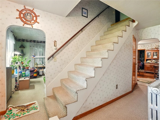 3912 Austinburg Rd, Ashtabula, OH 44004 - staircase with wallpapered walls, arched walkways, carpet floors, and radiator heating unit