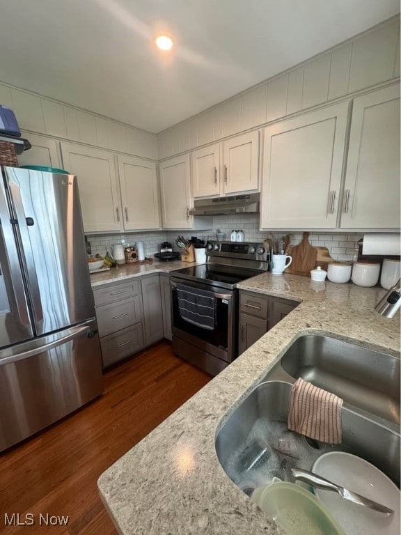 1505 N 14th St, Cambridge, OH 43725 - kitchen with stainless steel appliances, under cabinet range hood, a sink, tasteful backsplash, and dark wood-style floors