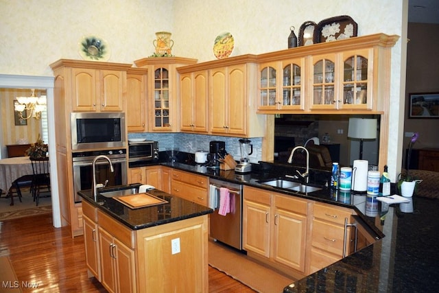 7711 Marewood Pl, Painesville, OH 44077 - kitchen with appliances with stainless steel finishes, a sink, wood finished floors, decorative backsplash, and dark stone countertops