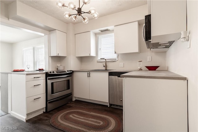 3525 Raymont Rd, University Heights, OH 44118 - kitchen with appliances with stainless steel finishes, a sink, dark wood finished floors, white cabinets, and a chandelier