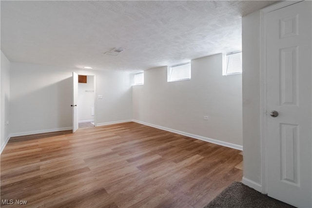 3525 Raymont Rd, University Heights, OH 44118 - basement with baseboards, light wood-style flooring, and a textured ceiling