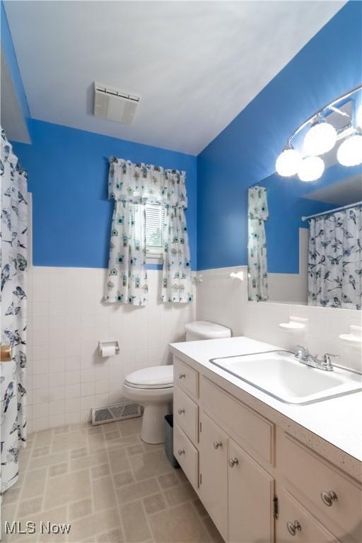 1922 W 38th St, Lorain, OH 44053 - bathroom with tile walls, vanity, toilet, a wainscoted wall, and a shower with curtain