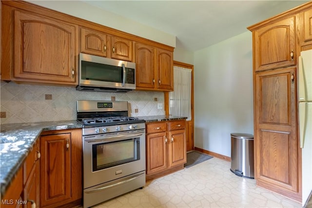731 39th St SW, Canton, OH 44706 - kitchen with appliances with stainless steel finishes, brown cabinets, decorative backsplash, and baseboards