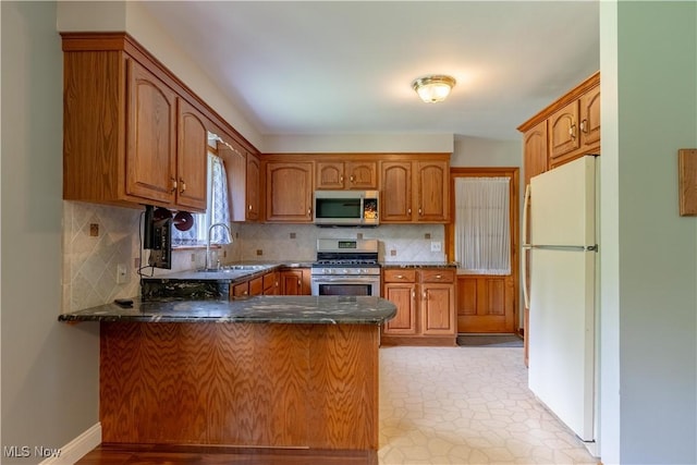 731 39th St SW, Canton, OH 44706 - kitchen with appliances with stainless steel finishes, a sink, a peninsula, brown cabinets, and decorative backsplash
