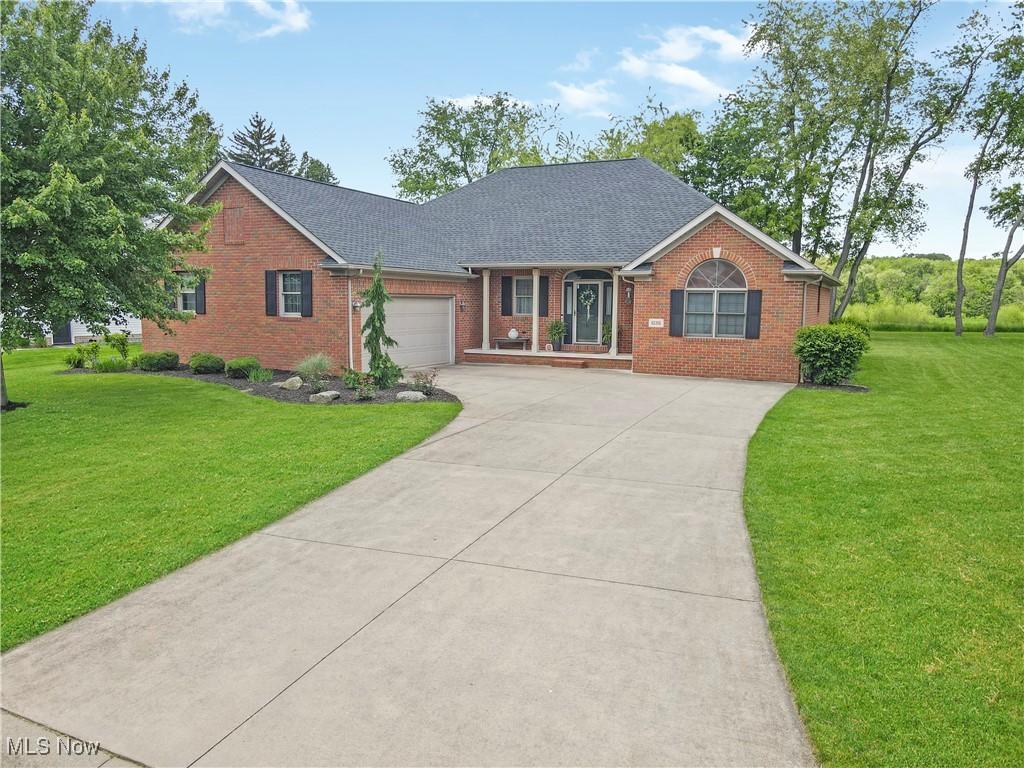 1135 Wheaton Cir NE, Massillon, OH 44646 - view of front facade with brick siding, driveway, a front lawn, a garage, and a shingled roof