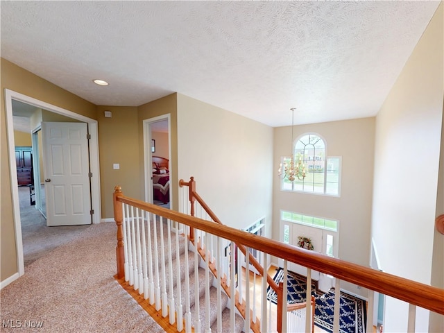 4171 Appleridge Ln, Richfield, OH 44286 - hall with an upstairs landing, light carpet, baseboards, a textured ceiling, and a chandelier