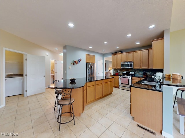 4171 Appleridge Ln, Richfield, OH 44286 - kitchen with appliances with stainless steel finishes, a breakfast bar area, a kitchen island, tasteful backsplash, and light tile patterned floors