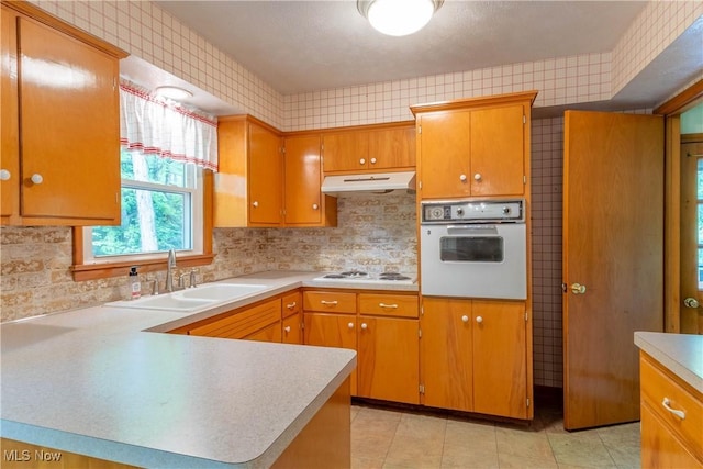 17444 Old State Rd, Middlefield, OH 44062 - kitchen with white appliances, a sink, under cabinet range hood, light countertops, and light tile patterned flooring