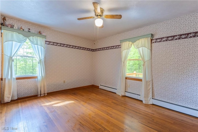 17444 Old State Rd, Middlefield, OH 44062 - empty room with hardwood / wood-style flooring, healthy amount of natural light, wallpapered walls, a ceiling fan, and baseboard heating