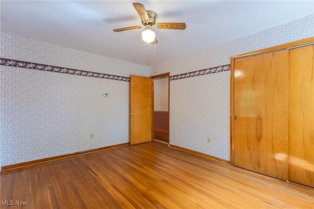 17444 Old State Rd, Middlefield, OH 44062 - unfurnished bedroom with wood finished floors, wallpapered walls, baseboards, and a ceiling fan