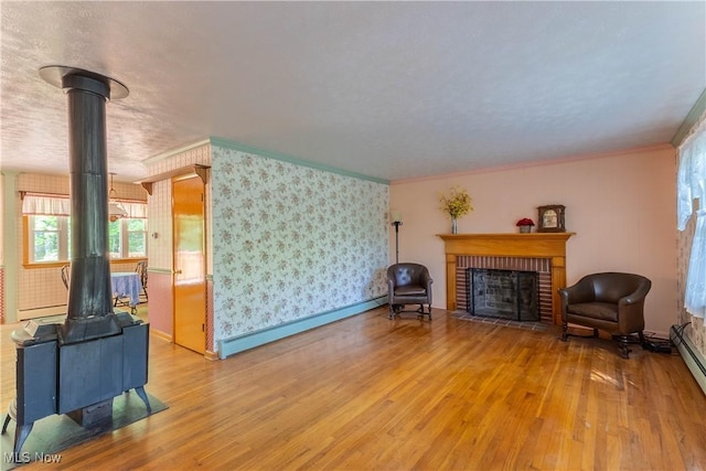 17444 Old State Rd, Middlefield, OH 44062 - living room with a wood stove, hardwood / wood-style floors, baseboard heating, ornamental molding, and wallpapered walls