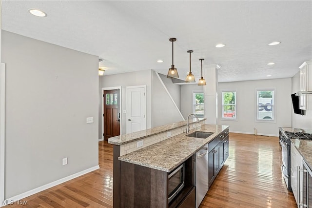 2450 Tremont Ave, Cleveland, OH 44113 - kitchen with appliances with stainless steel finishes, a center island with sink, light wood-style floors, recessed lighting, and white cabinetry