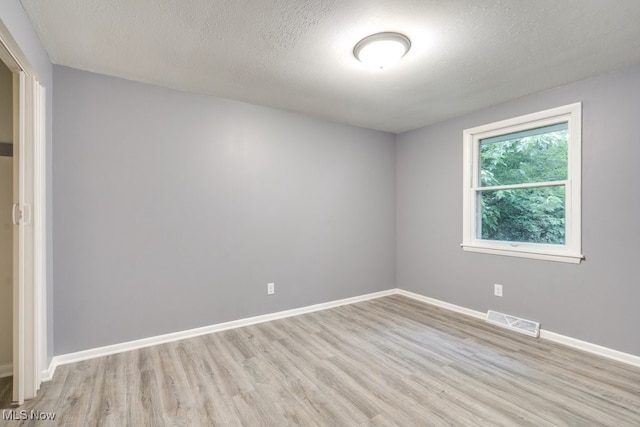 2318 3rd St SE, Canton, OH 44707 - spare room featuring light wood-style flooring, baseboards, and a textured ceiling