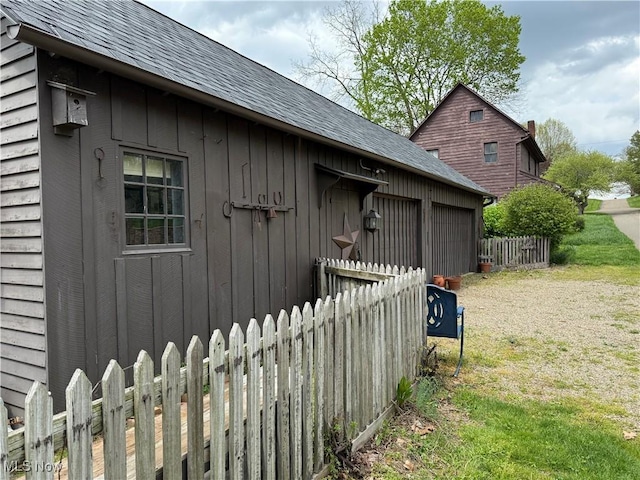 199 E 3rd St, Zoar, OH 44697 - view of home's exterior featuring a garage, board and batten siding, roof with shingles, and an outdoor structure