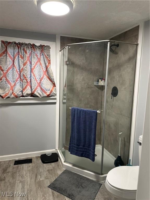 408 W Paradise St, Orrville, OH 44667 - bathroom featuring a stall shower, wood finished floors, toilet, and a textured ceiling