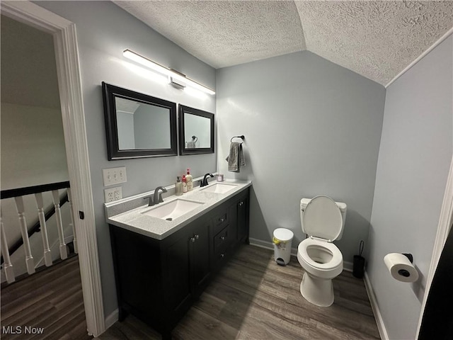 408 W Paradise St, Orrville, OH 44667 - full bath with double vanity, lofted ceiling, a textured ceiling, wood finished floors, and toilet