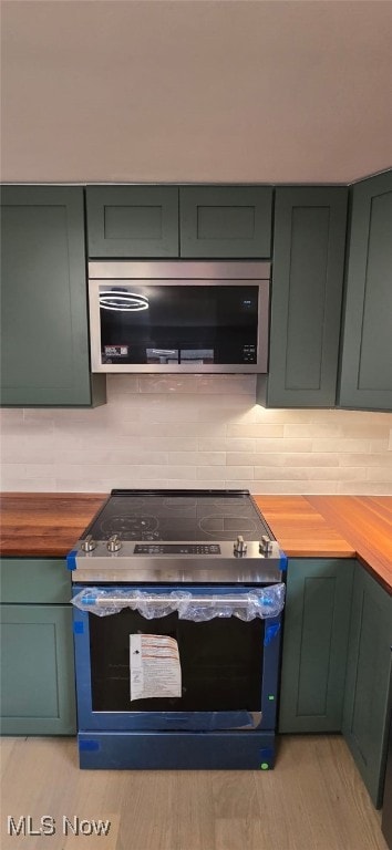 809 4th St, Brilliant, OH 43913 - kitchen with stainless steel appliances, butcher block countertops, green cabinetry, and decorative backsplash