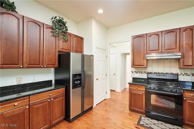 3563 Saint Andrews Ln, Richfield, OH 44286 - kitchen with gas stove, stainless steel fridge, under cabinet range hood, light wood-style flooring, and dark stone counters