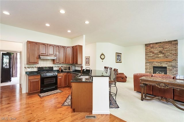 3563 Saint Andrews Ln, Richfield, OH 44286 - kitchen featuring black range with gas cooktop, stainless steel microwave, a sink, under cabinet range hood, and a peninsula