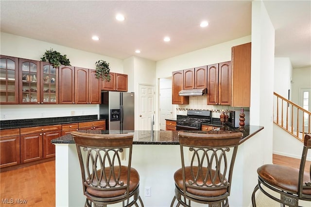 3563 Saint Andrews Ln, Richfield, OH 44286 - kitchen with stainless steel refrigerator with ice dispenser, gas stove, under cabinet range hood, light wood-type flooring, and a peninsula