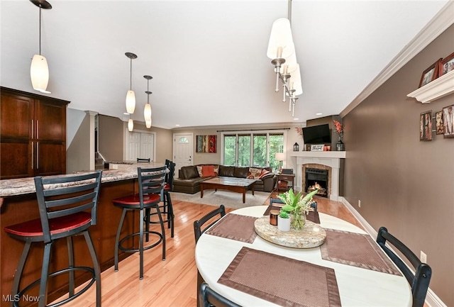 3576 Ellen Dr, Akron, OH 44312 - dining area with light wood finished floors, a warm lit fireplace, baseboards, and ornamental molding