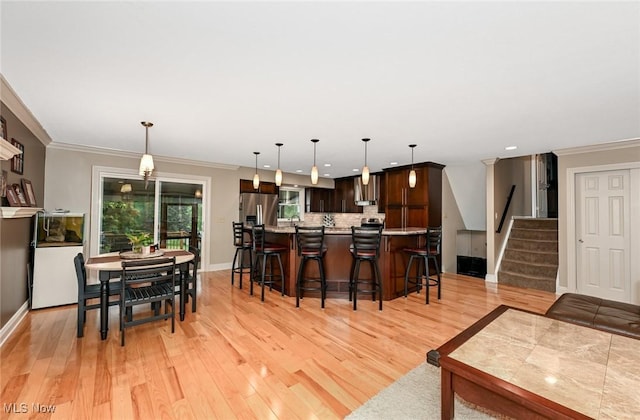 3576 Ellen Dr, Akron, OH 44312 - kitchen featuring dark brown cabinetry, a breakfast bar area, light wood-style flooring, light countertops, and decorative backsplash