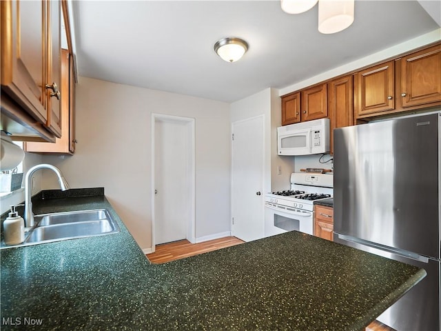 4482 Ranchview Ave, North Olmsted, OH 44070 - kitchen featuring white appliances, a sink, brown cabinets, dark countertops, and light wood-type flooring