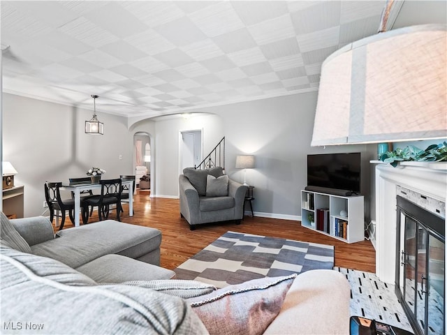 4482 Ranchview Ave, North Olmsted, OH 44070 - living area featuring arched walkways, a glass covered fireplace, wood finished floors, stairs, and baseboards