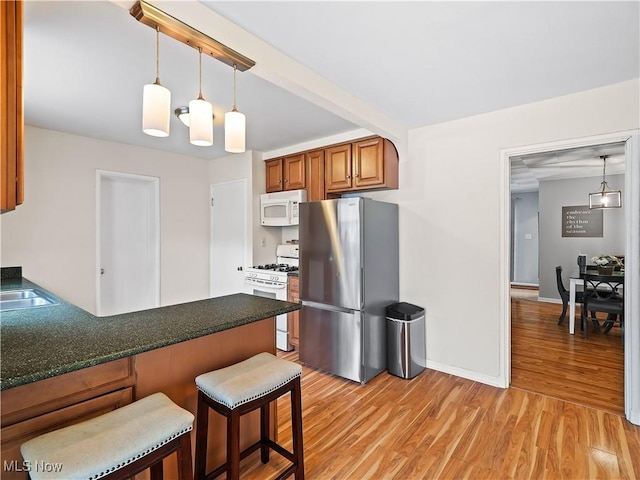 4482 Ranchview Ave, North Olmsted, OH 44070 - kitchen with white appliances, light wood finished floors, a breakfast bar, a peninsula, and dark countertops