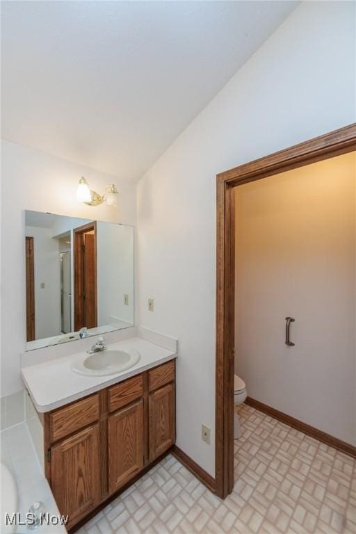 14250 Reserve Ln, Middleburg Heights, OH 44130 - full bath featuring lofted ceiling, toilet, vanity, baseboards, and brick patterned flooring