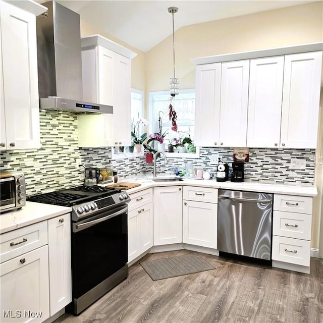 6363 Lockhaven Dr, Brook Park, OH 44142 - kitchen featuring stainless steel appliances, wall chimney exhaust hood, a sink, vaulted ceiling, and light countertops