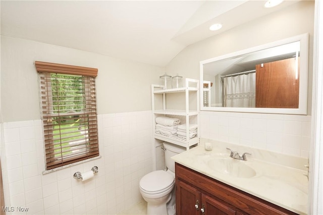 1087 Madrid Dr, Akron, OH 44313 - full bath with tile walls, vanity, vaulted ceiling, toilet, and a wainscoted wall