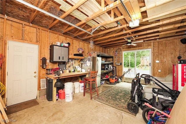 1087 Madrid Dr, Akron, OH 44313 - garage with wood walls, a ceiling fan, freestanding refrigerator, and a workshop area