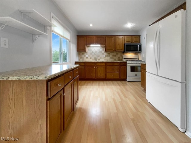 2330 Judy Dr, Parma, OH 44134 - kitchen with white appliances, brown cabinetry, a sink, light wood-type flooring, and backsplash