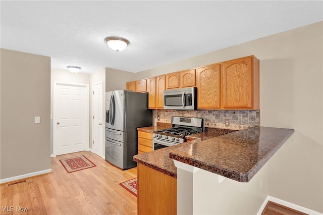 3527 Perry Ct, Lorain, OH 44053 - kitchen with appliances with stainless steel finishes, decorative backsplash, light wood finished floors, and a peninsula