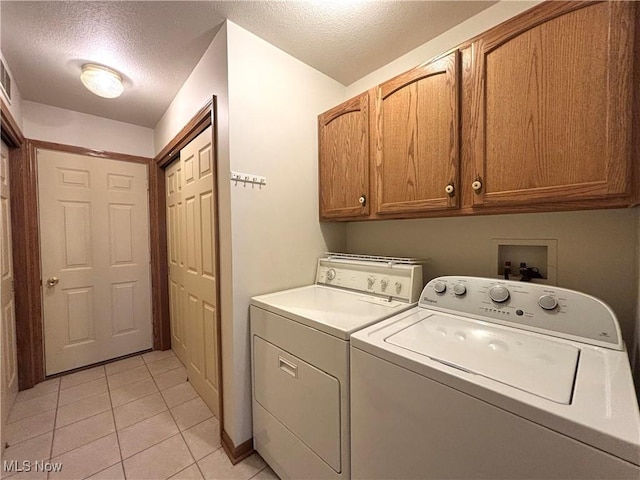 39 Village Ct, Columbiana, OH 44408 - washroom with cabinet space, washing machine and dryer, a textured ceiling, and light tile patterned floors