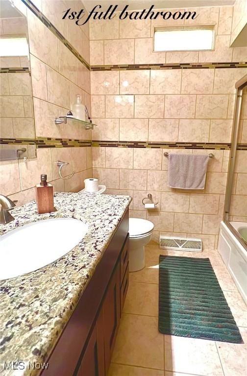6101 Laurent Dr, Parma, OH 44129 - bathroom featuring tile walls, vanity, toilet, tile patterned floors, and shower / washtub combination