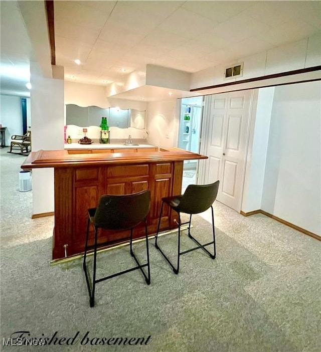 6101 Laurent Dr, Parma, OH 44129 - kitchen with light colored carpet, baseboards, a sink, a breakfast bar, and light countertops