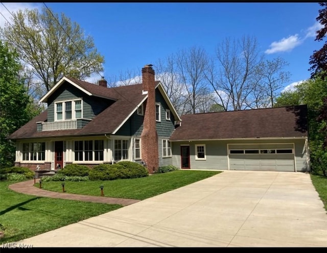 7434 Birkner Dr, Kent, OH 44240 - view of front facade featuring concrete driveway, an attached garage, a chimney, and a front lawn
