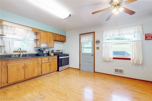 213 Pico St, Steubenville, OH 43952 - kitchen with gas stove, a sink, light wood finished floors, dark countertops, and brown cabinetry