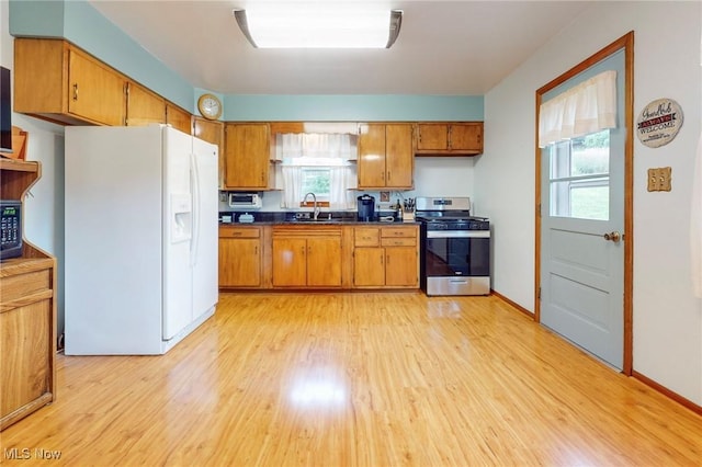 213 Pico St, Steubenville, OH 43952 - kitchen with white fridge with ice dispenser, stainless steel range with gas cooktop, dark countertops, brown cabinets, and light wood-type flooring