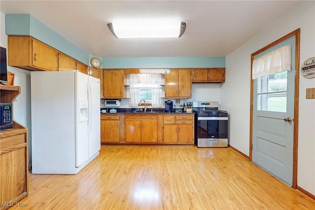213 Pico St, Steubenville, OH 43952 - kitchen featuring stainless steel gas range, white fridge with ice dispenser, dark countertops, a sink, and brown cabinetry