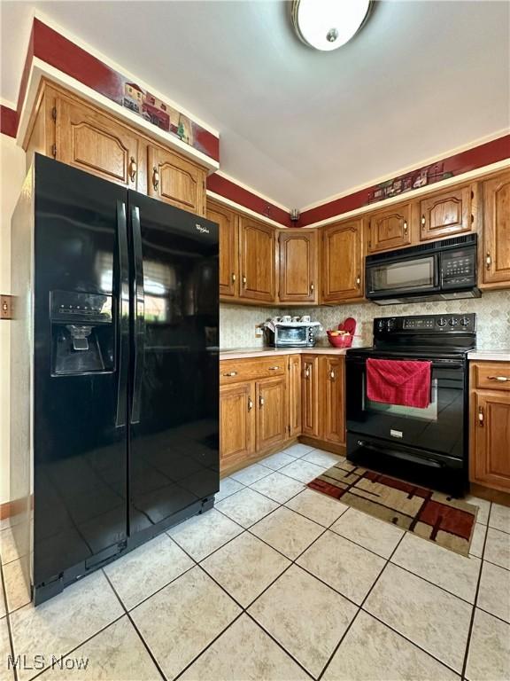 2308 Bears Den Rd, Youngstown, OH 44511 - kitchen with black appliances, brown cabinetry, light tile patterned floors, light countertops, and decorative backsplash
