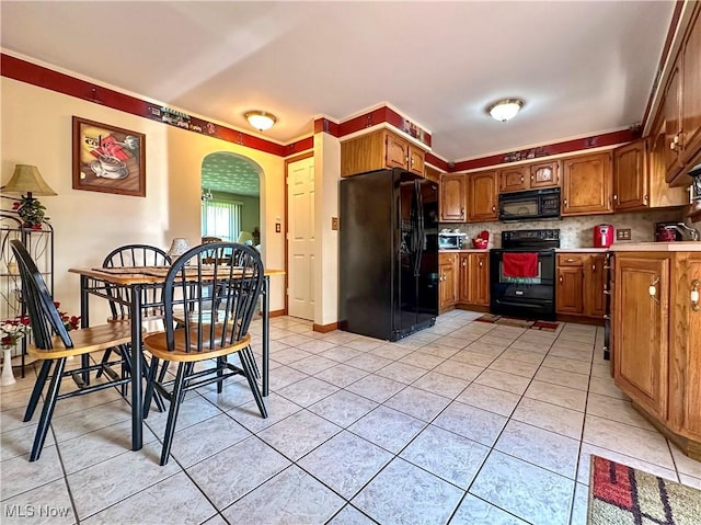 2308 Bears Den Rd, Youngstown, OH 44511 - kitchen featuring black appliances, arched walkways, light tile patterned floors, light countertops, and brown cabinets