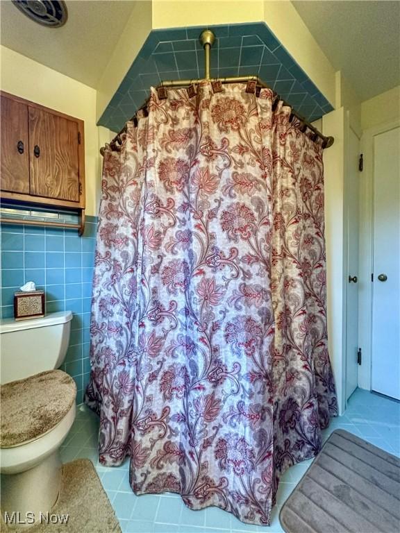 2308 Bears Den Rd, Youngstown, OH 44511 - full bathroom featuring tile patterned flooring, tile walls, toilet, wainscoting, and a shower with shower curtain