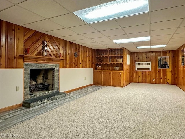 2308 Bears Den Rd, Youngstown, OH 44511 - unfurnished living room with wooden walls, a stone fireplace, baseboards, heating unit, and carpet floors