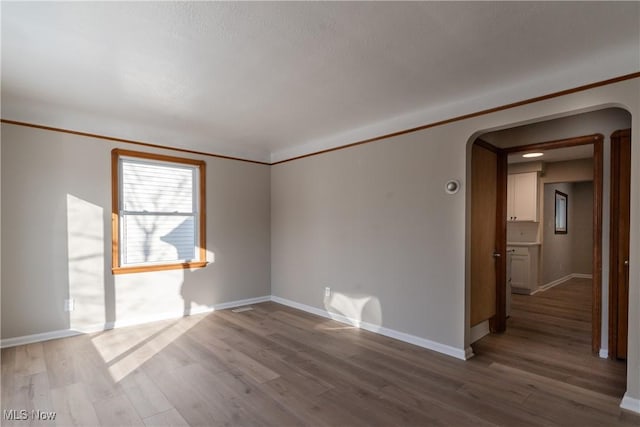 4827 E 88th St, Garfield Heights, OH 44125 - empty room featuring arched walkways, baseboards, and wood finished floors