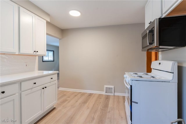 4827 E 88th St, Garfield Heights, OH 44125 - kitchen featuring white range with electric stovetop, stainless steel microwave, white cabinets, tasteful backsplash, and light wood-style flooring