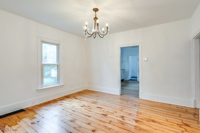 235 Elm St, Oberlin, OH 44074 - spare room with a chandelier, light wood-style floors, and baseboards